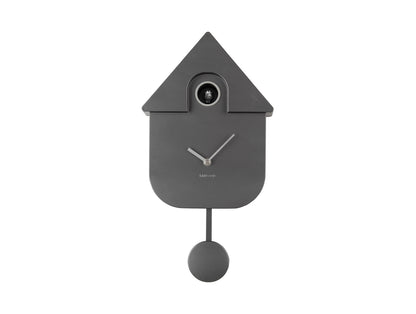 Horloge murale design, gris foncé métallisé, avec ouverture pour l'heure et balancier suspendu.