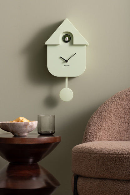Horloge murale coucou dans un boîtier vert clair avec pendule et aspect bois