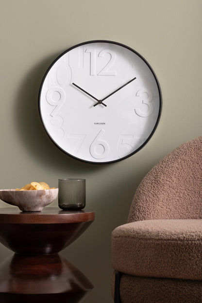 Horloge murale blanche avec aiguilles noires et chiffres en relief sur le bord