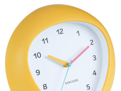Karlsson Horloge murale, gros plan : cadre jaune, cadran blanc avec aiguilles et chiffres.