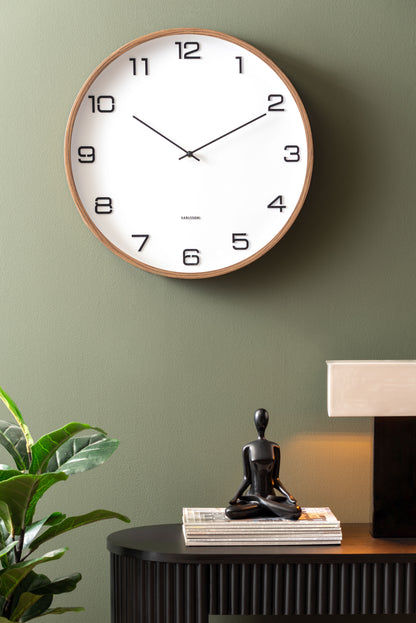 Horloge murale sur un mur avec un cadran blanc et un cadre aspect bois