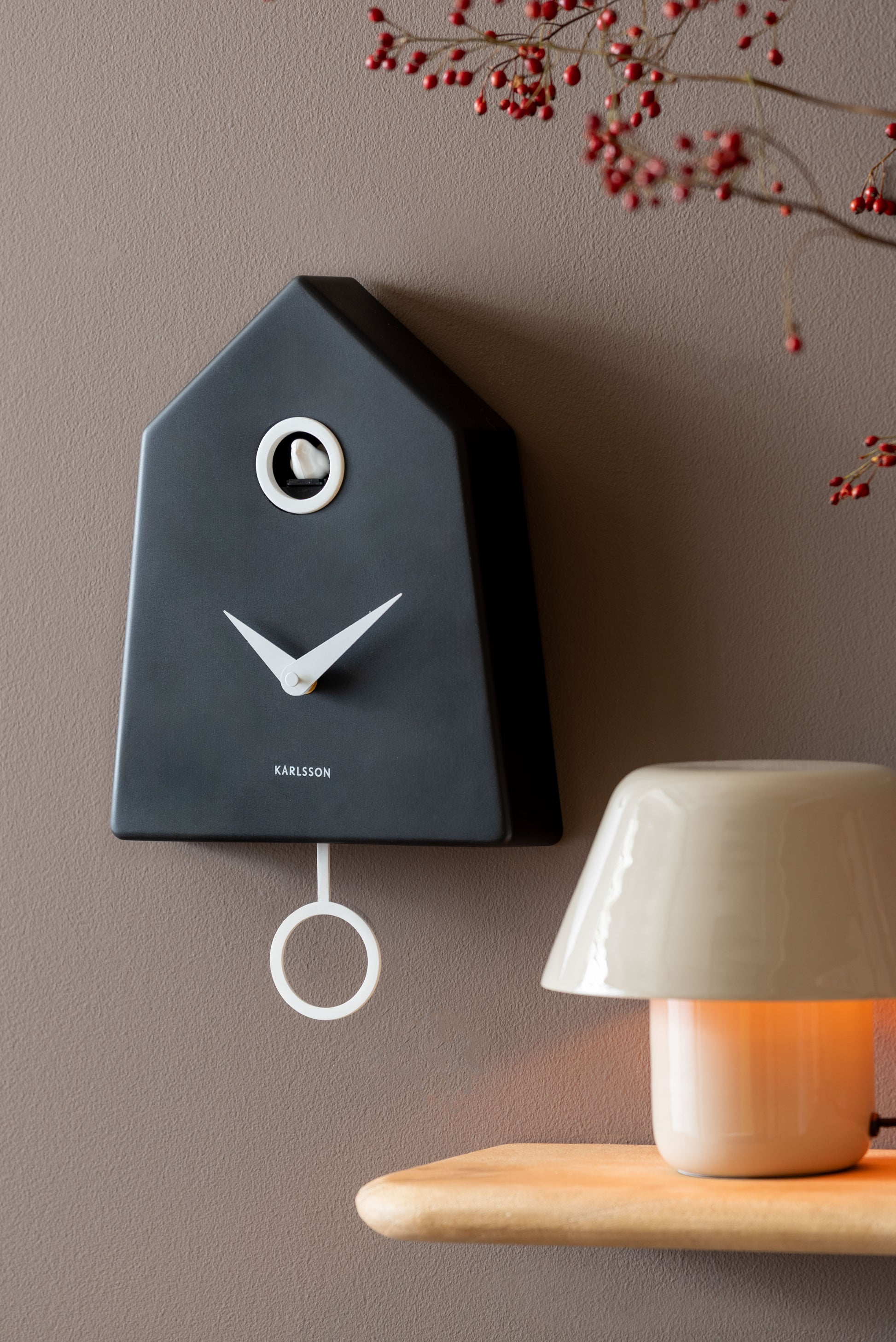 Horloge murale à coucou Karlsson Grafico au mur, boîtier noir avec aiguilles et balancier