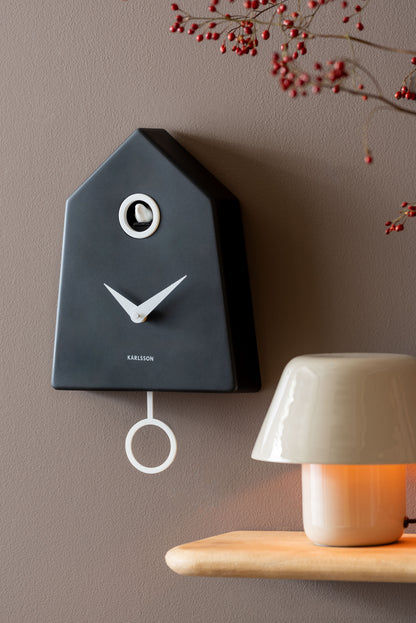 Horloge murale à coucou Karlsson Grafico au mur, boîtier noir avec aiguilles et balancier