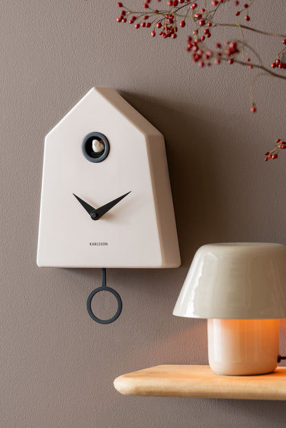 Karlsson Grafico-Wanduhr in warmgrau an der Wand, mit Pendelring und Zeigern