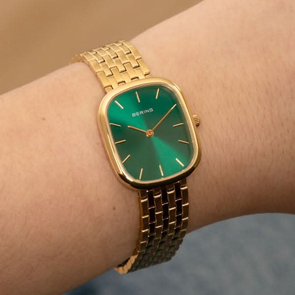 Montre pour femme au poignet avec cadran vert et bracelet à maillons dorés