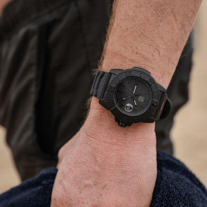 Montre pour homme au poignet : montre de sport noire avec cadran sombre et bracelet noir.