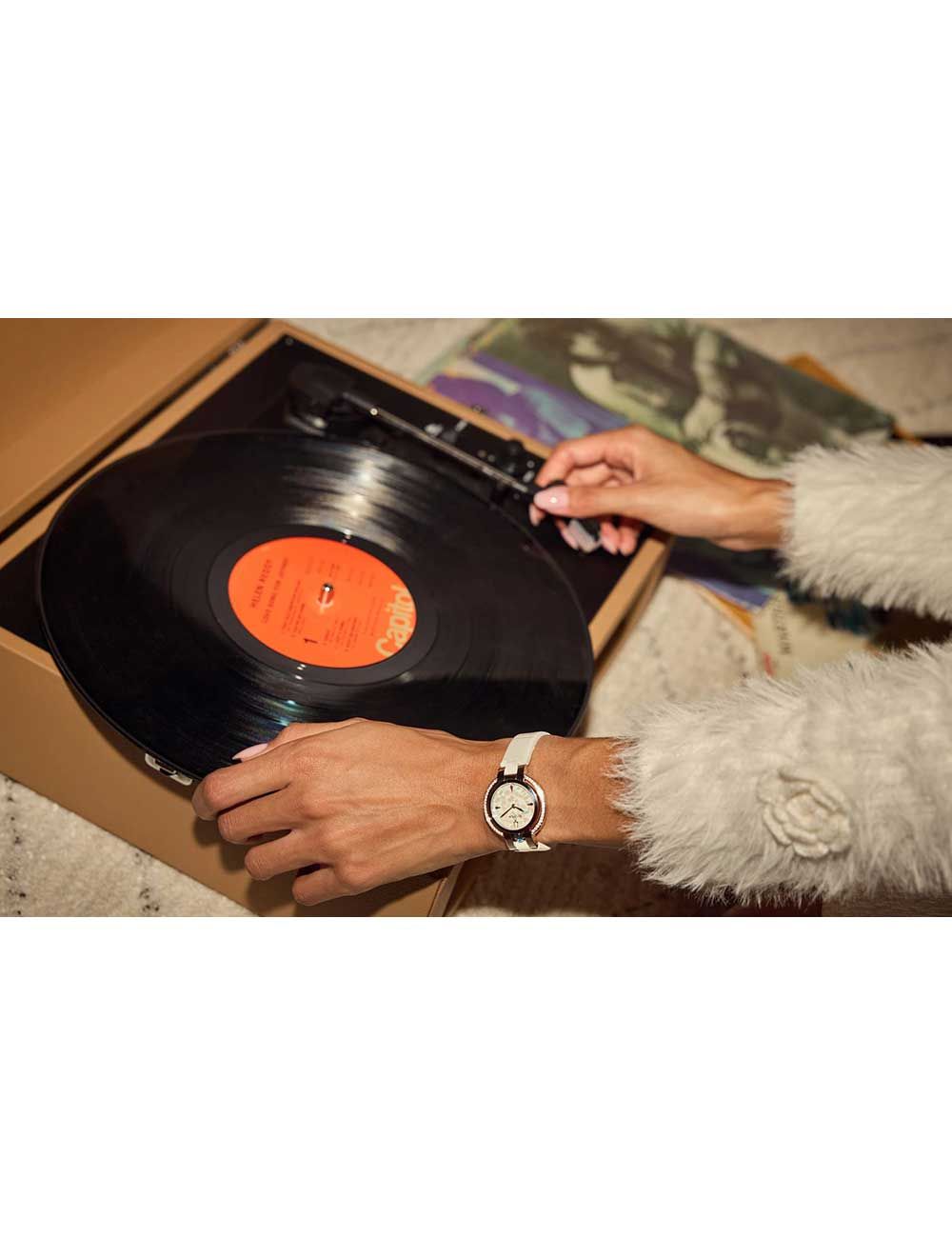 Person trägt Bulova Damenuhr mit weißem Lederarmband beim Hantieren mit Vinylplatte