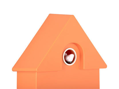 Orange väggklocka i husdesign, närbild av det runda fönstret