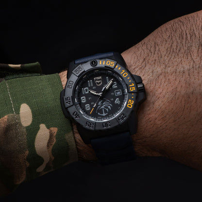 Montre pour homme au poignet : boîtier noir, bracelet bleu foncé, index luminescents et date.