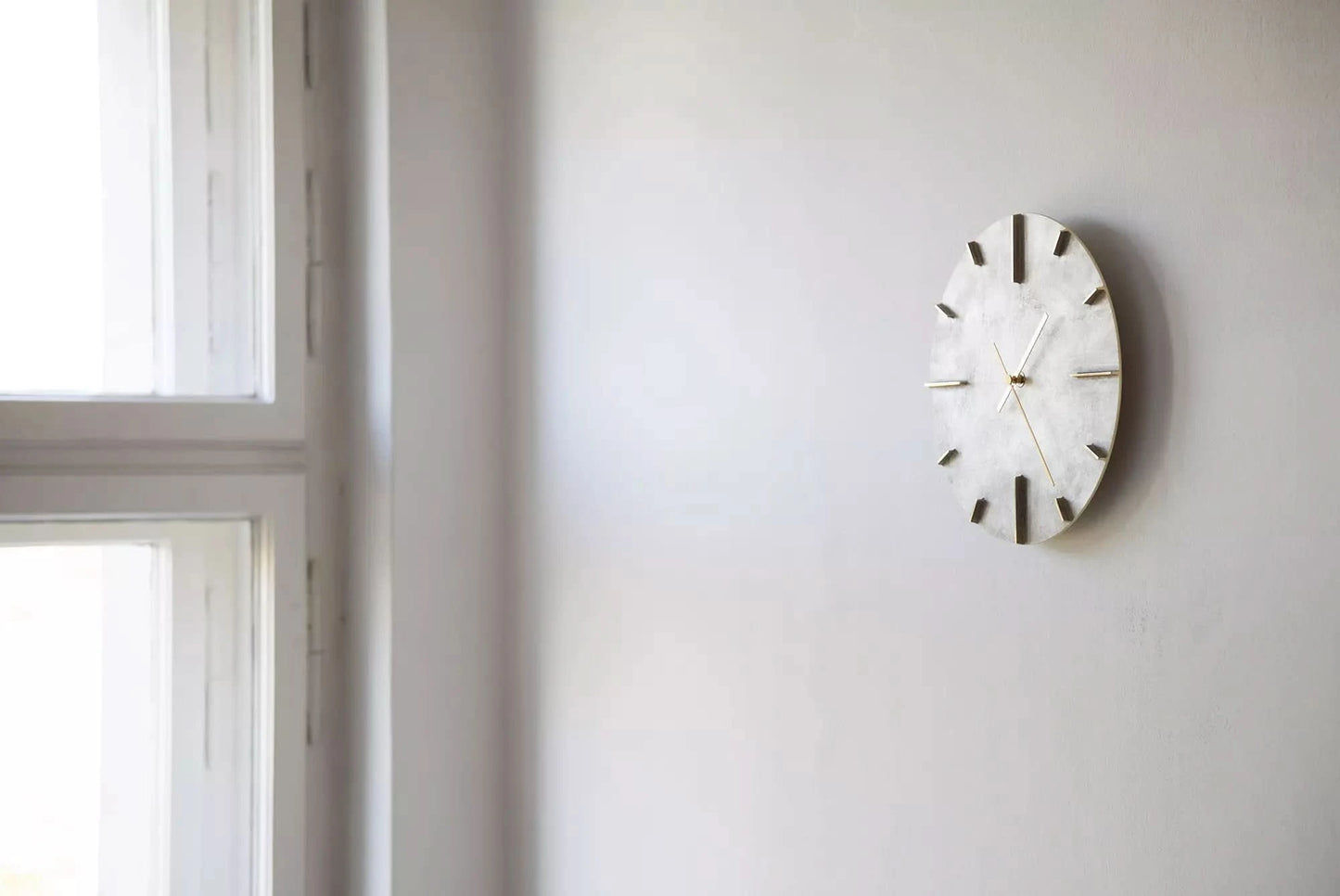 Horloge murale en métal avec cadran gris foncé et aiguilles fines fixée au mur