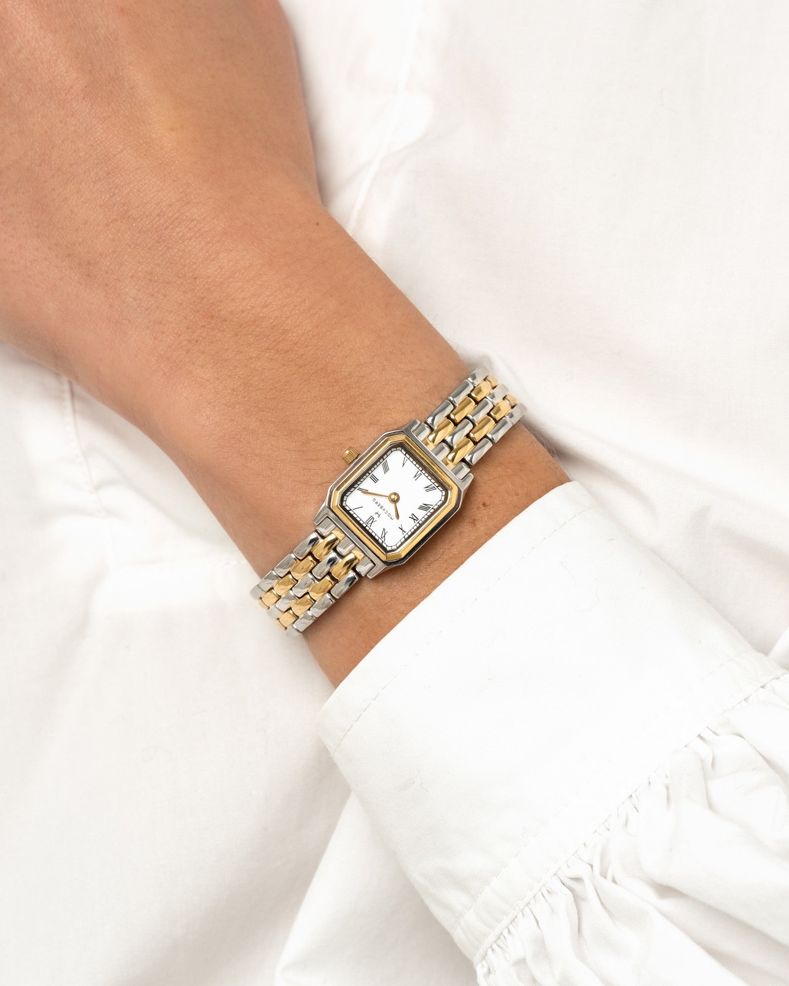 Damenarmbanduhr am Handgelenk mit weißem Zifferblatt und Edelstahl-Gliederarmband in Silber/Gold