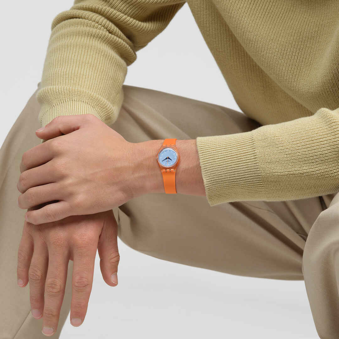 Damenuhr am Handgelenk: hellblaues Zifferblatt und orangefarbenes transparentes Armband