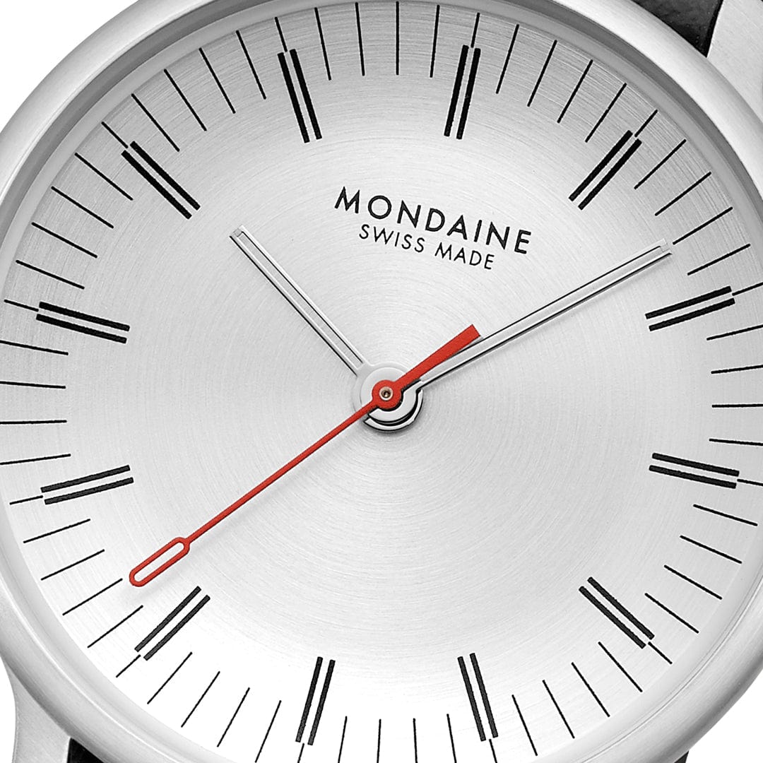Mondaine Damenuhr Nahaufnahme: weißes Zifferblatt mit roten Zeigern und Indexen