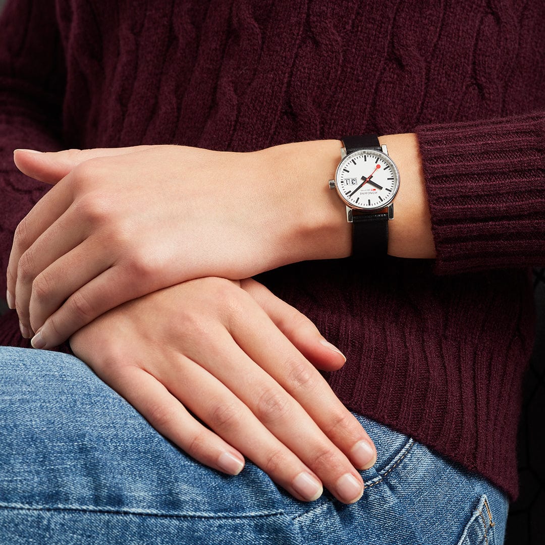 Damenarmbanduhr am Handgelenk mit schwarzem Lederarmband und weißem Zifferblatt