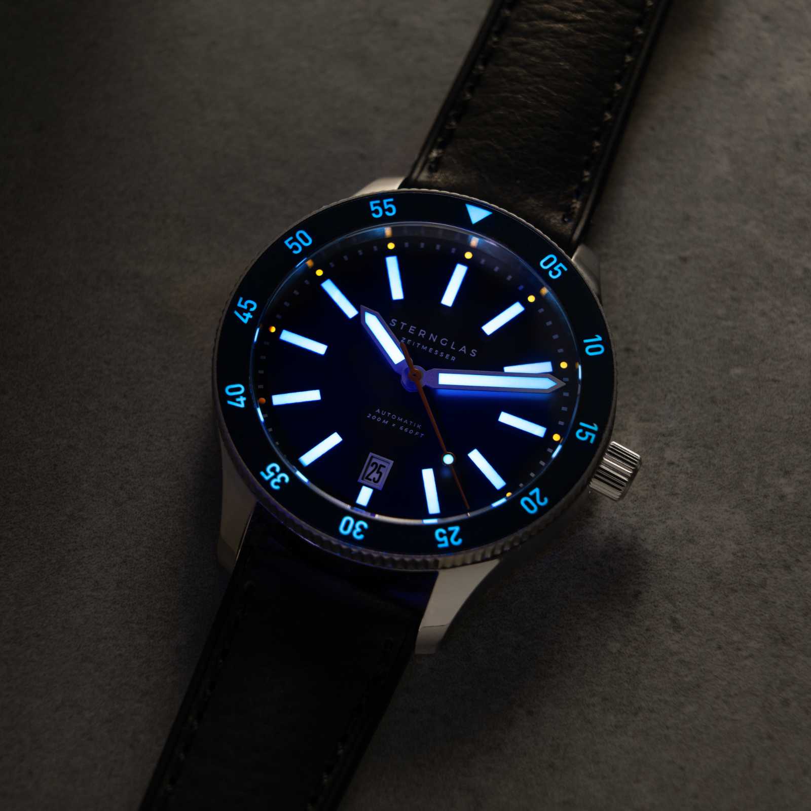 Montre pour homme avec cadran bleu, index luminescents et boîtier argenté, bracelet bleu.