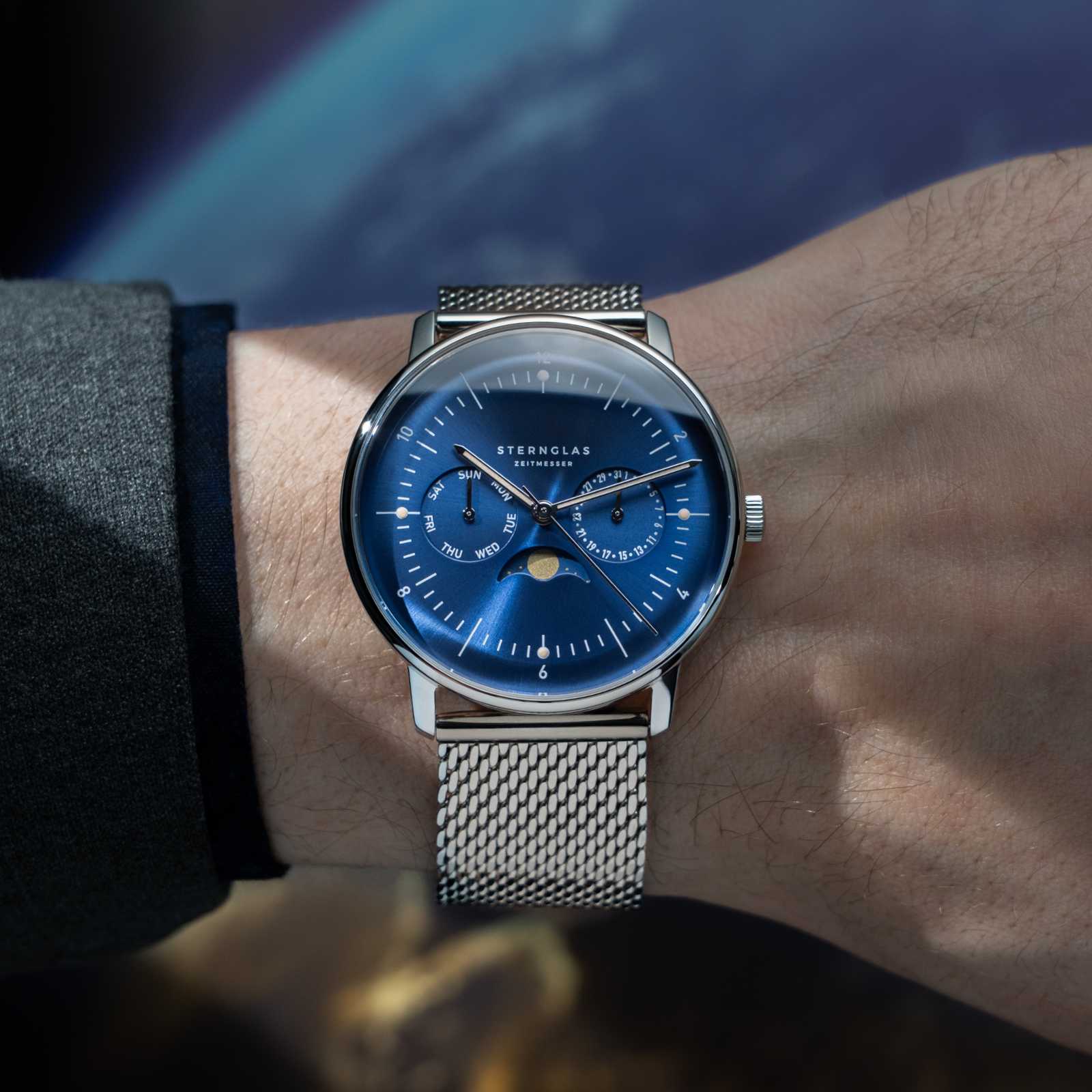 Bracelet de montre pour homme avec cadran bleu et bracelet en maille argentée, porté au poignet
