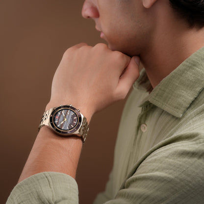 Herrenarmbanduhr am Handgelenk mit beigem Metallarmband und dunklem Zifferblatt