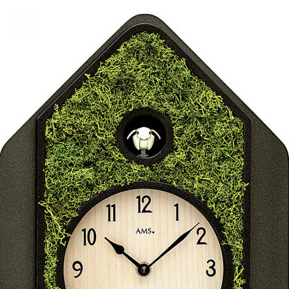 Pendule de maison avec mousse verte, cadran et figurine de coucou sur le dessus