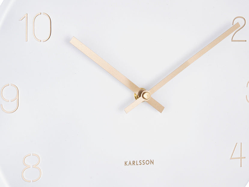 Horloge murale blanche avec aiguilles dorées et chiffres gravés, détail frontal