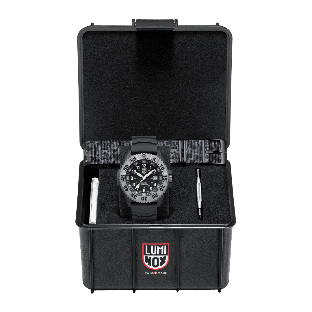 Montre homme dans un étui noir ouvert : boîtier noir, cadran sombre et bracelet en textile.