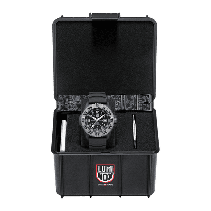 Montre homme dans un étui noir ouvert : boîtier noir, cadran sombre et bracelet en textile.