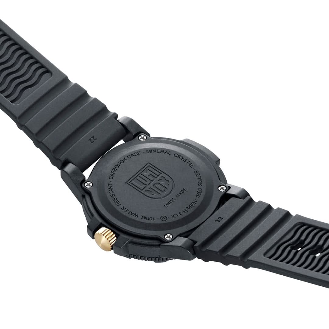 Vue arrière : fond de boîtier noir, couronne dorée et bracelet en caoutchouc texturé