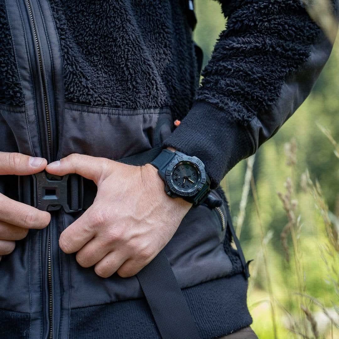 Montre de sport portée au poignet avec bracelet noir et cadran sombre.