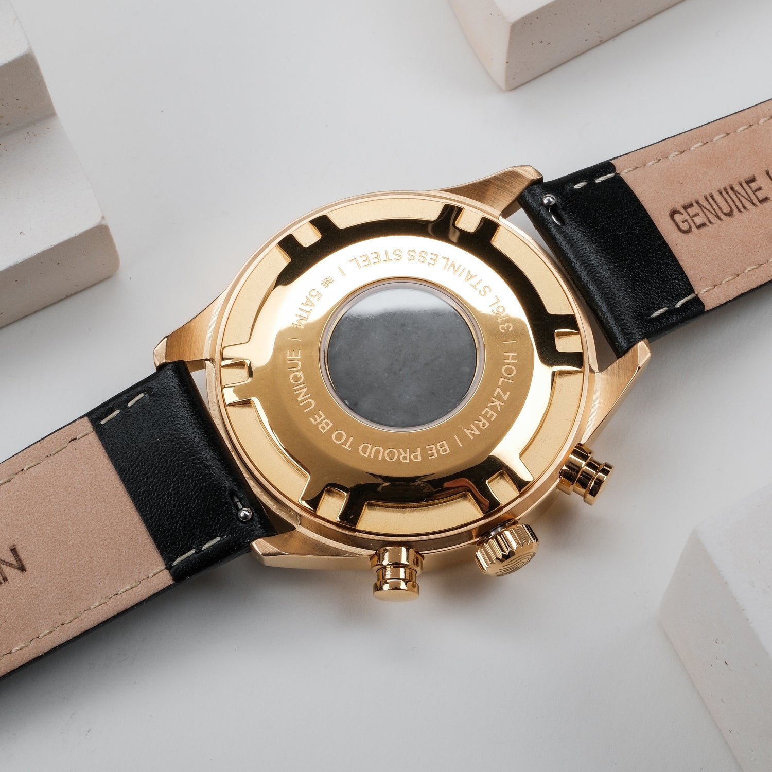 Holzkern Armbanduhr mit goldenem Gehäuseboden und schwarzem Lederband, darunter Buckle