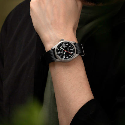 Herrenarmbanduhr am Handgelenk mit schwarzem Textilband und schwarzem Zifferblatt