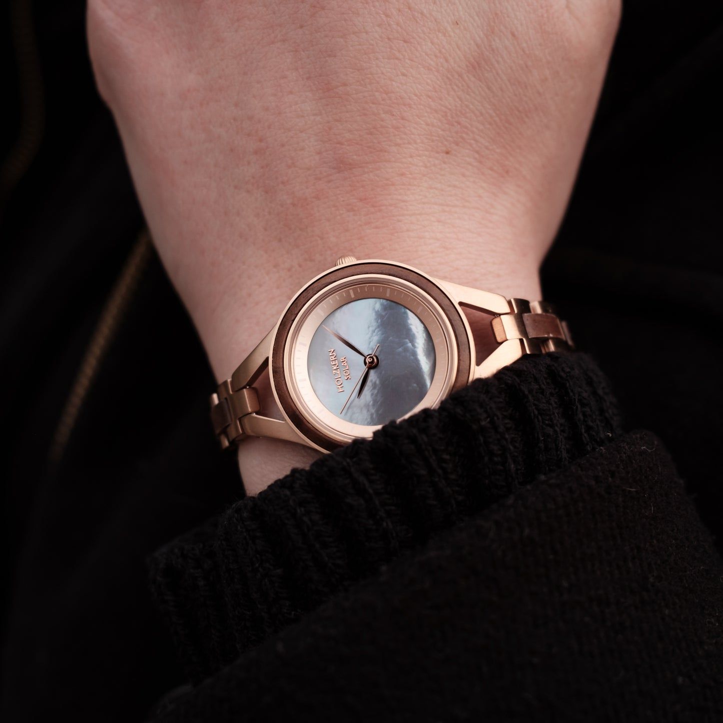 Damenarmbanduhr mit roséfarbenem Gehäuse, blauem Zifferblatt und Gliederarmband am Handgelenk