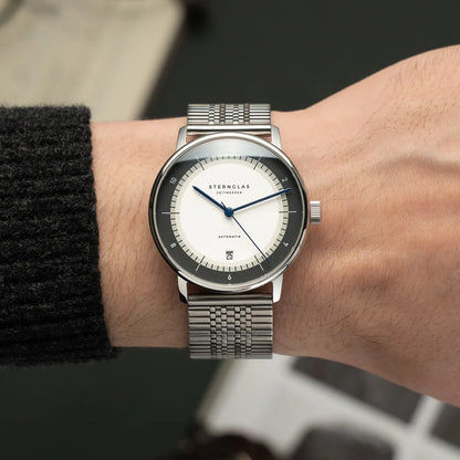 Herrenarmbanduhr Sternglas Naos am Handgelenk, silbernes Milanaiseband, weißes Zifferblatt
