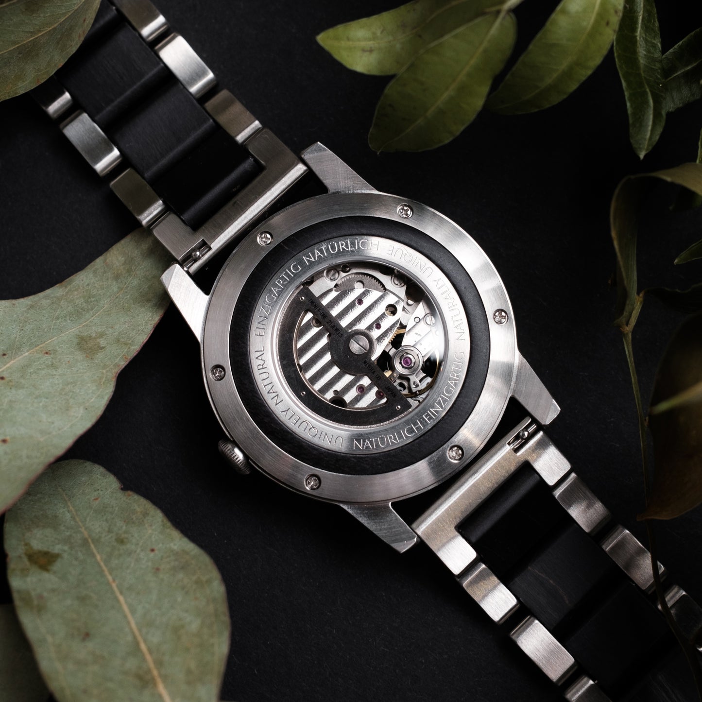 Herrenuhr-Rückseite mit sichtbarem Automatikwerk, silbernem Gehäuse und schwarzem Armband