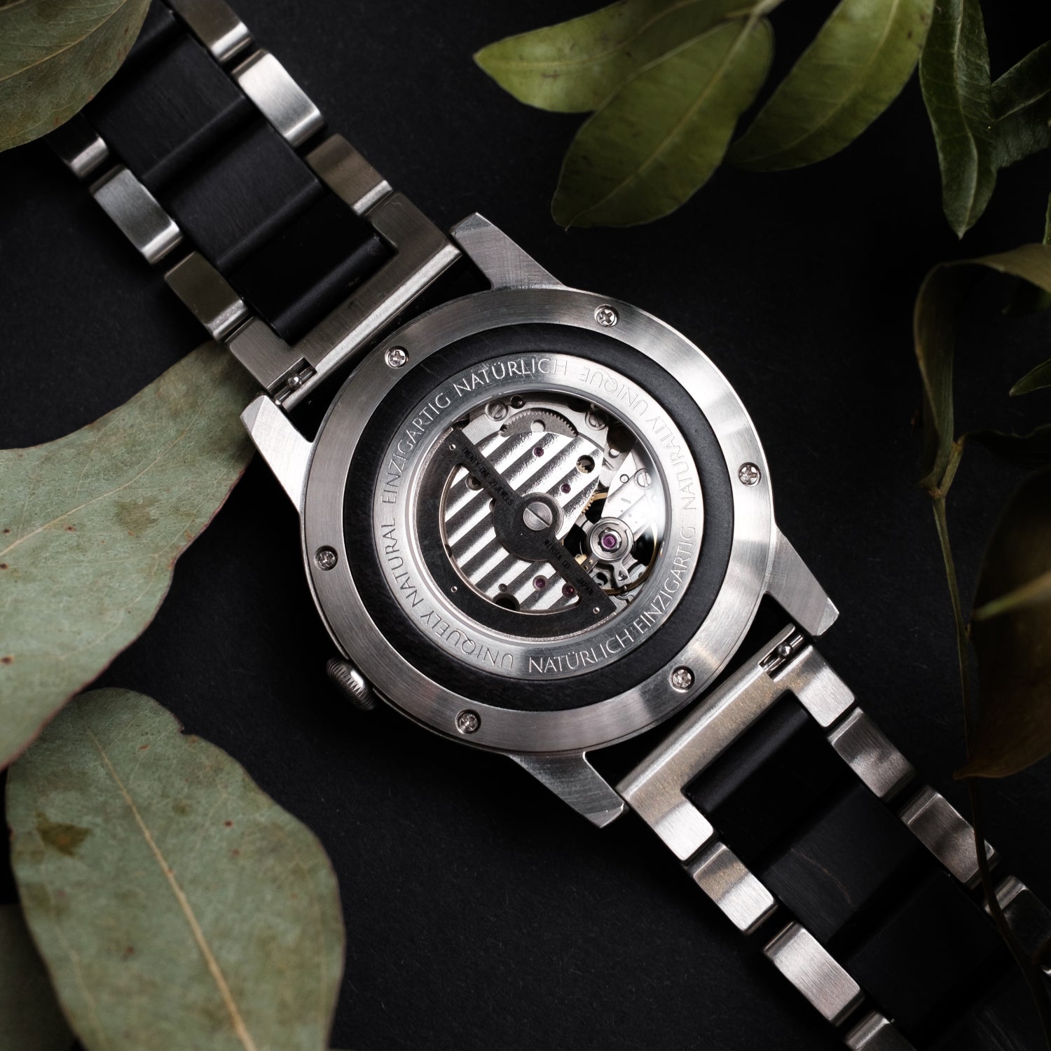 Herrenuhr-Rückseite mit sichtbarem Automatikwerk, silbernem Gehäuse und schwarzem Armband