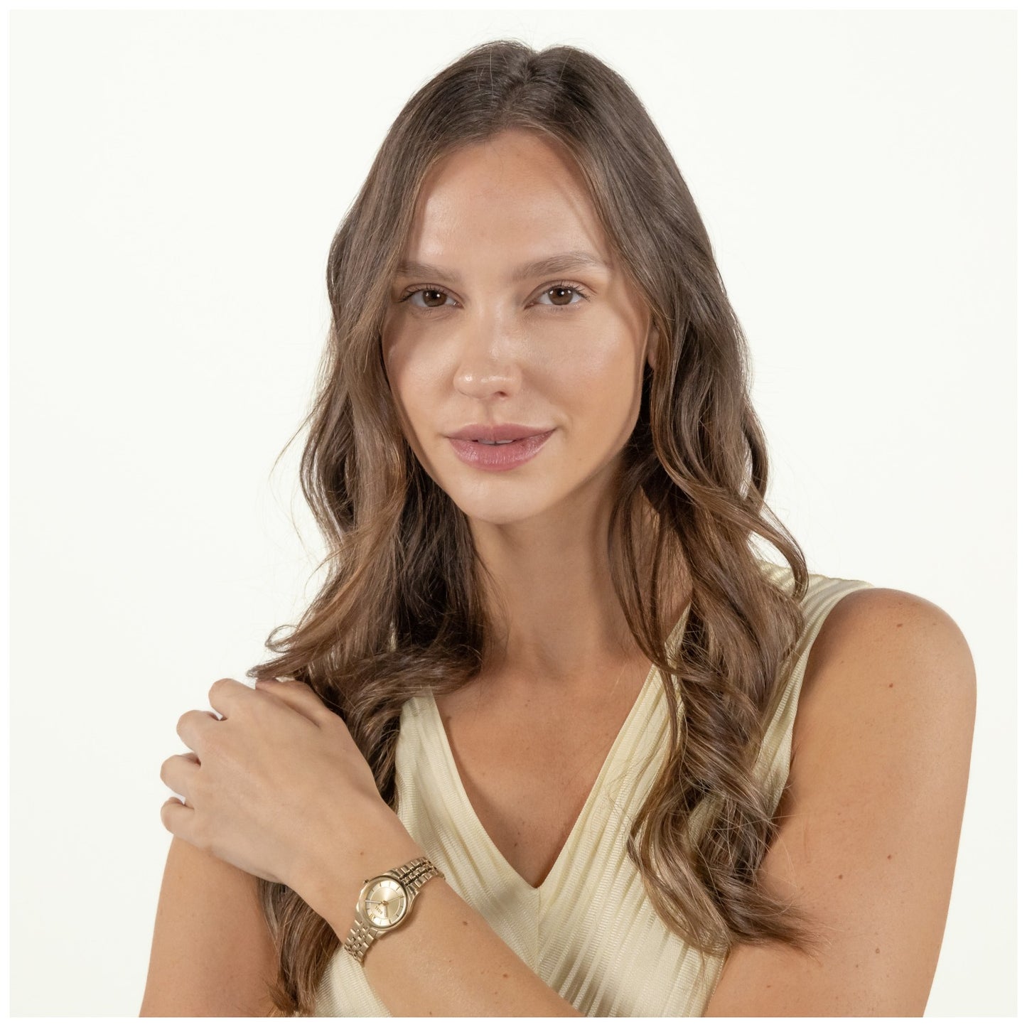 Damenarmbanduhr am Handgelenk, rundes goldfarbenes Zifferblatt, Gliederarmband mit Faltschließe.