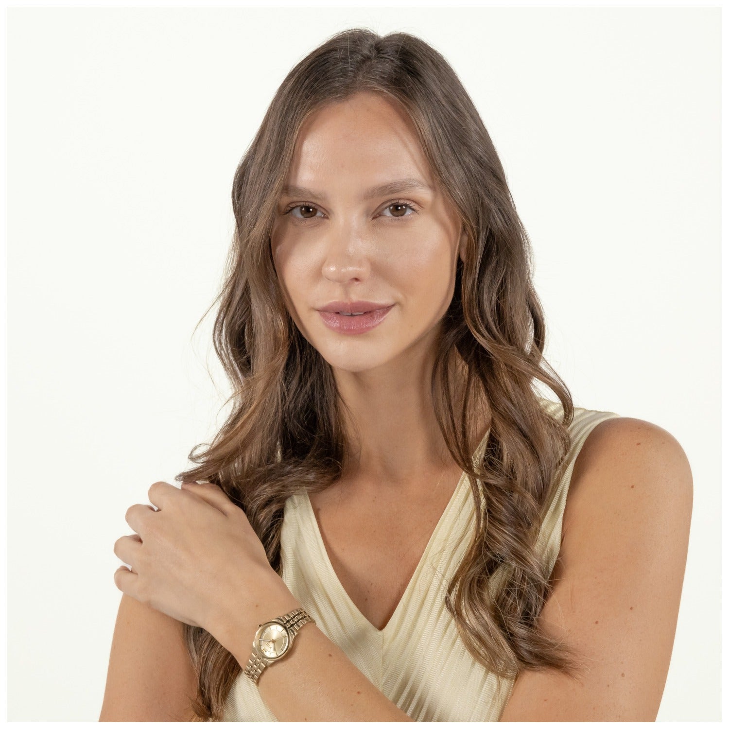 Damenarmbanduhr am Handgelenk, rundes goldfarbenes Zifferblatt, Gliederarmband mit Faltschließe.