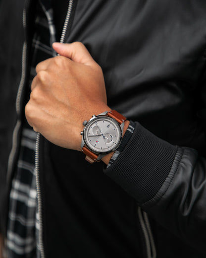 Herrenarmbanduhr mit grauem Zifferblatt und braunem Lederarmband, Krone sichtbar