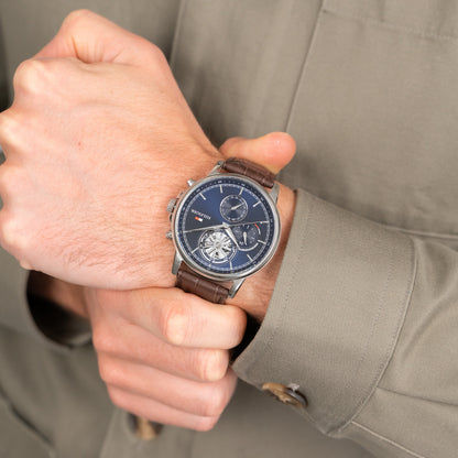 Herrenarmbanduhr am Handgelenk, blaues Zifferblatt mit Subdials, braunes Lederband.