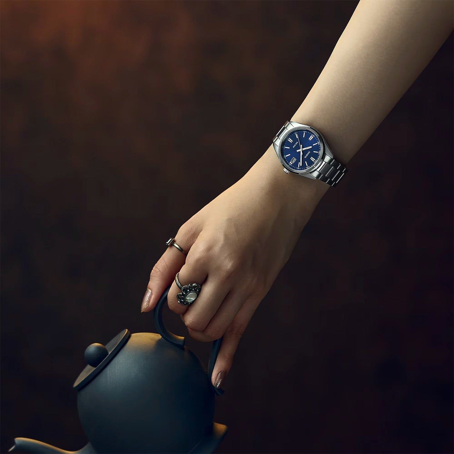 Casio Armbanduhr am Handgelenk, blaues Zifferblatt mit Datumsanzeige, Edelstahlarmband