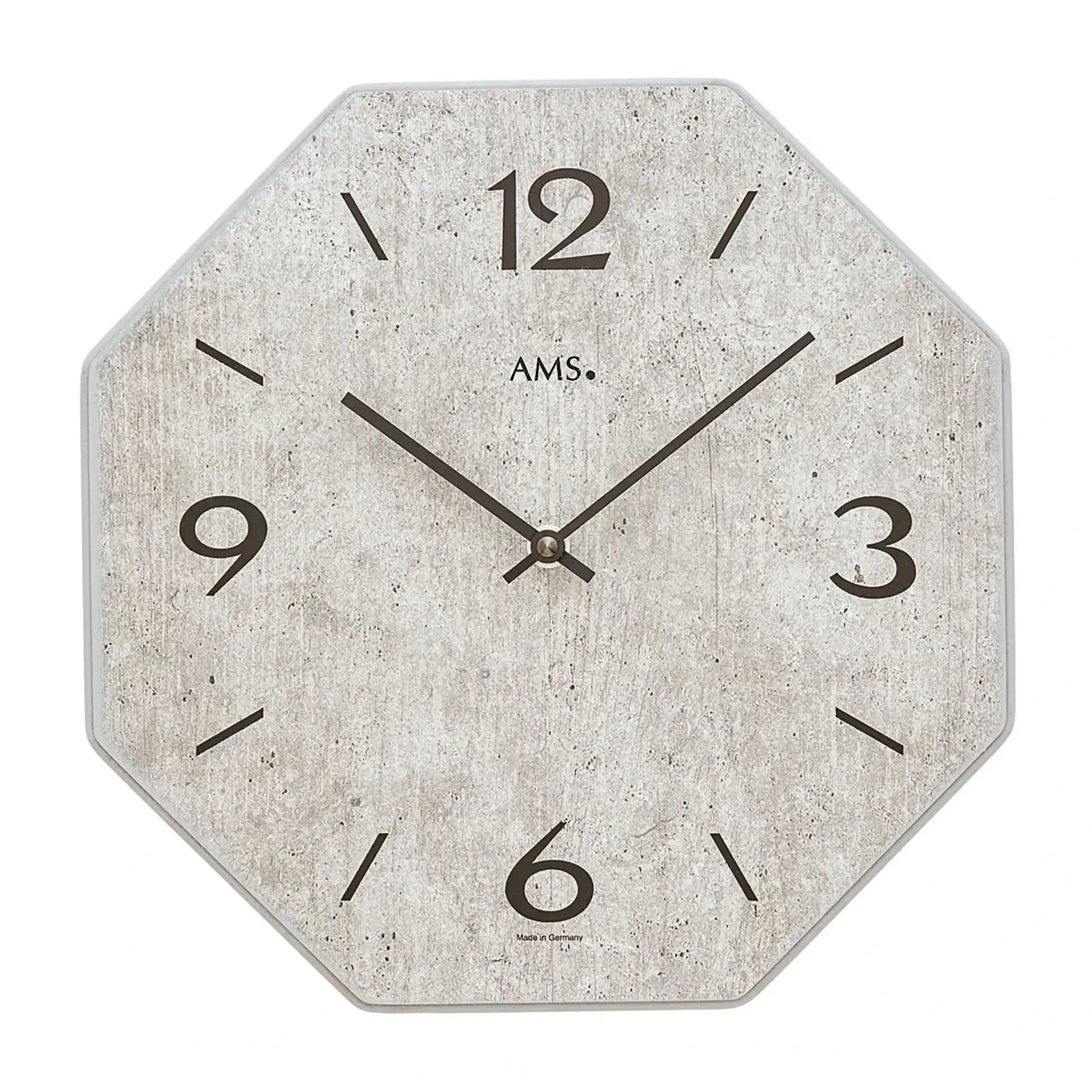 Horloge murale avec cadran gris, chiffres 1-12, aiguilles et logo AMS.