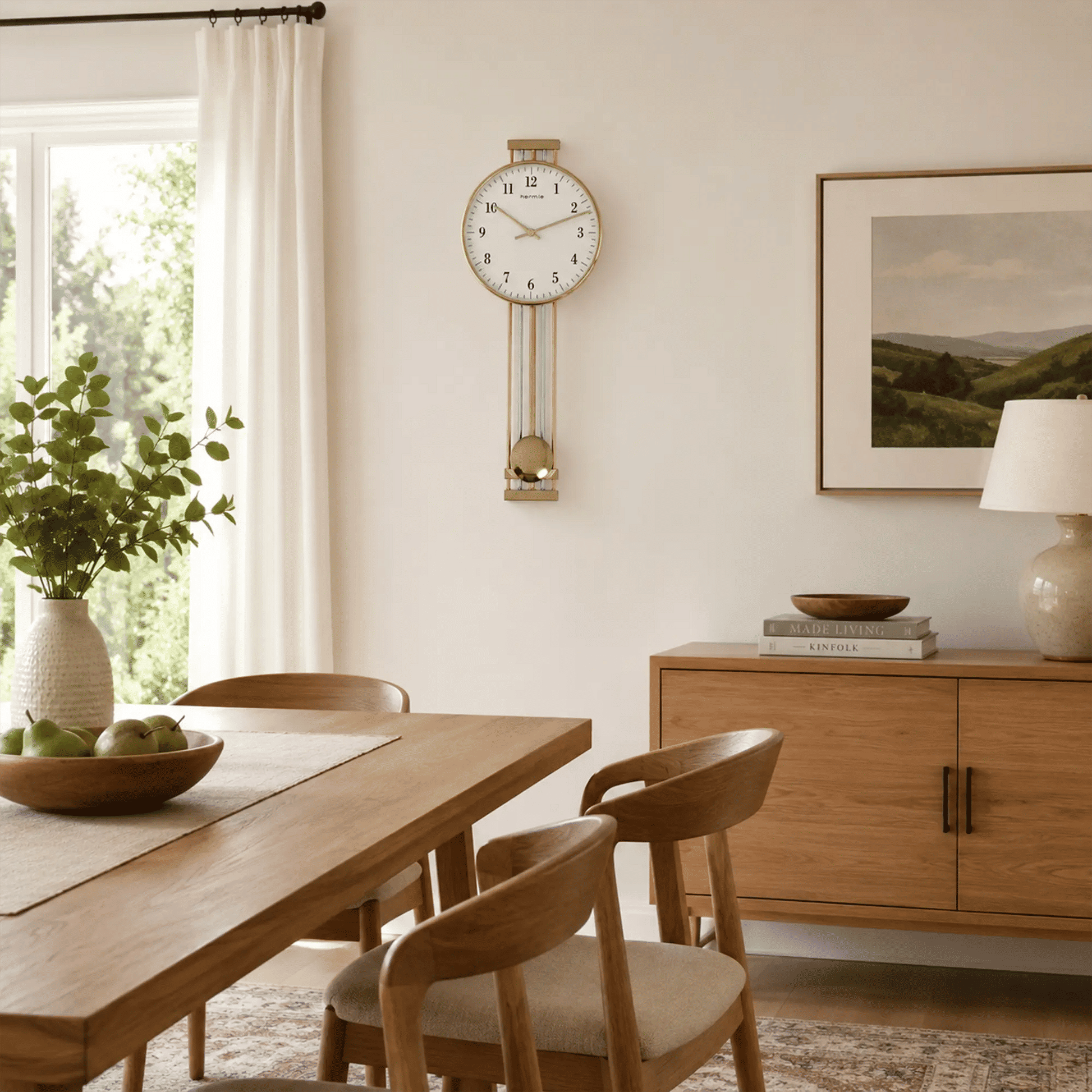 Wanduhr an der Wand mit goldenem Rahmen, weißem Zifferblatt und drei Pendelstäben.