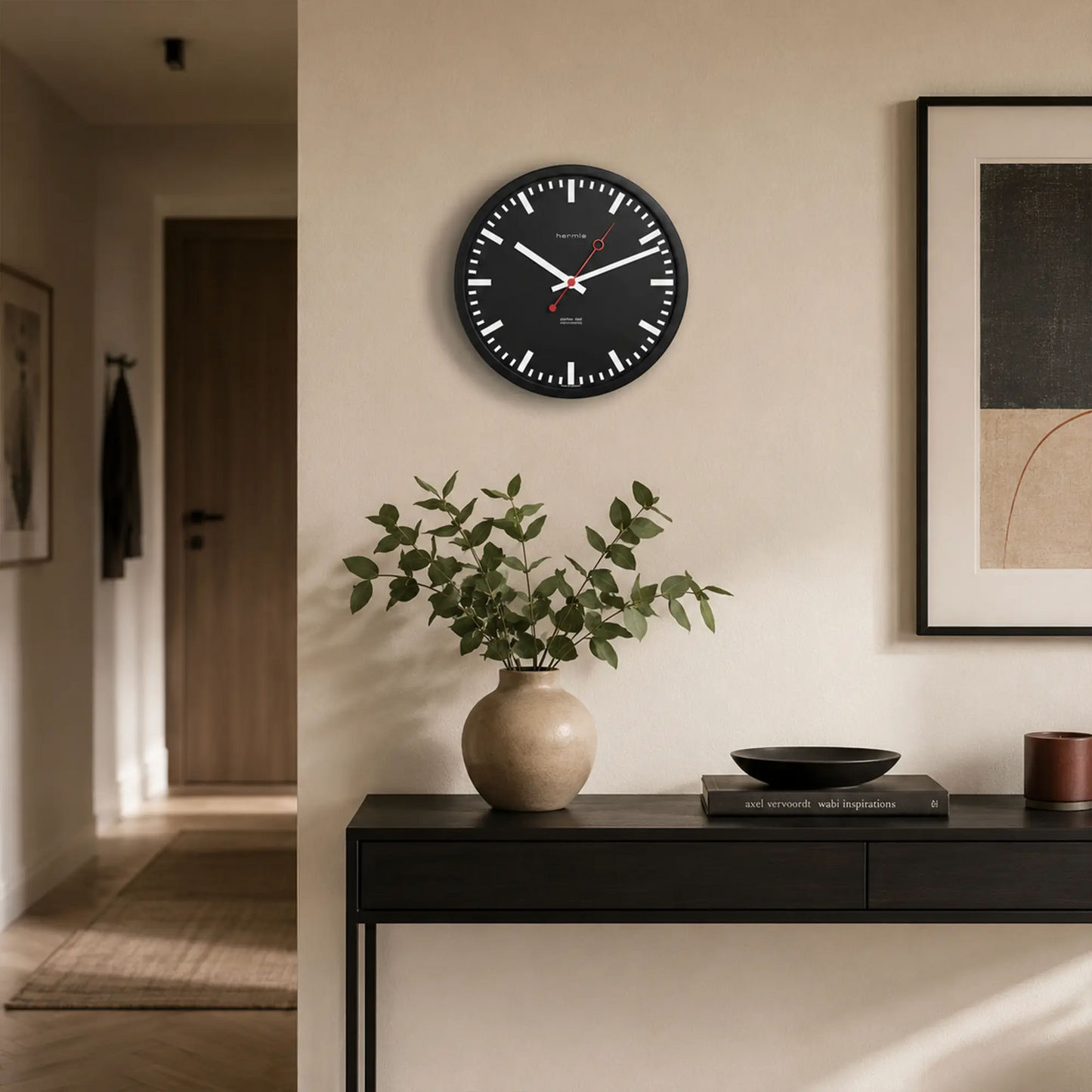 Wanduhr an der Wand: schwarzes Zifferblatt, rote Sekundenzeigerspitze, weiße Striche.