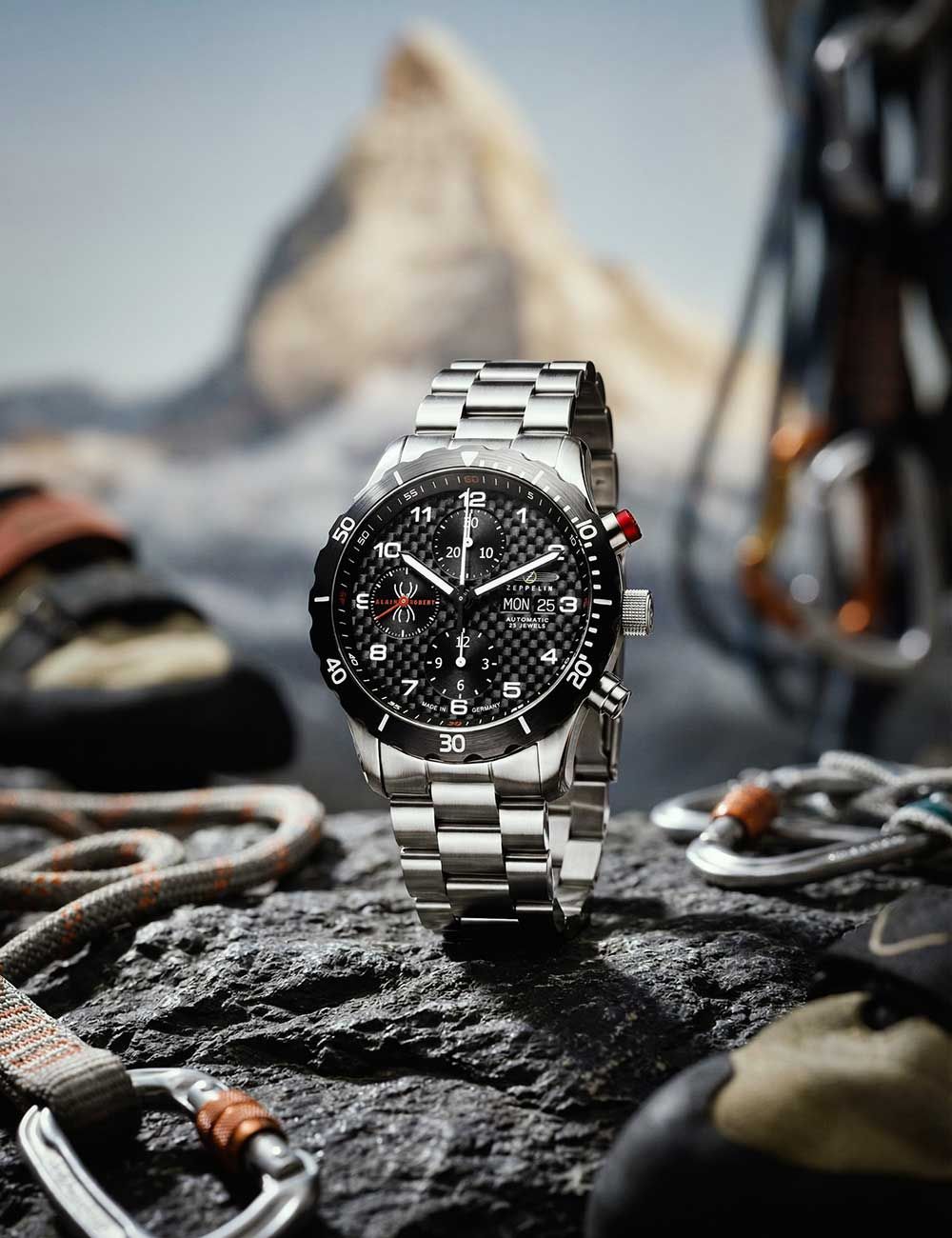 Herrenarmbanduhr mit schwarzem Zifferblatt und silbernem Edelstahlarmband auf Felsen