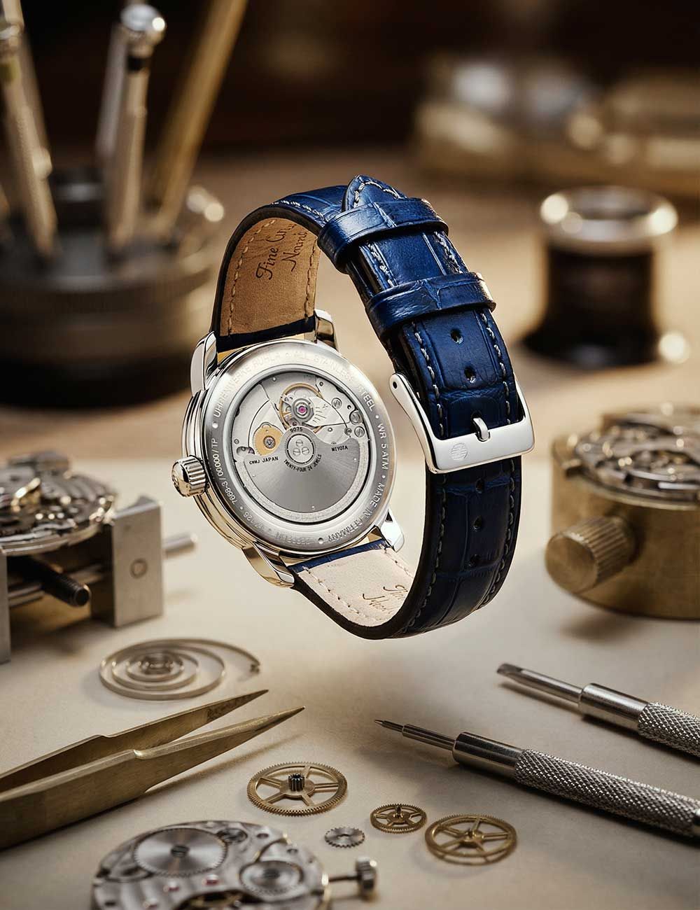Herrenarmbanduhr mit blauem Lederarmband und sichtbarem Uhrwerk im Gehäuse