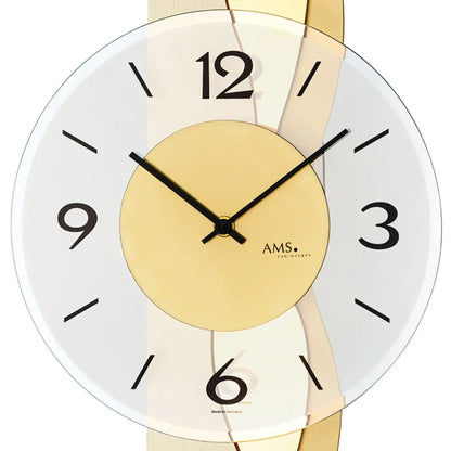 Nahansicht Wanduhr: weißes Zifferblatt, goldfarbene Mitte mit AMS-Logo, facettiertes Glas