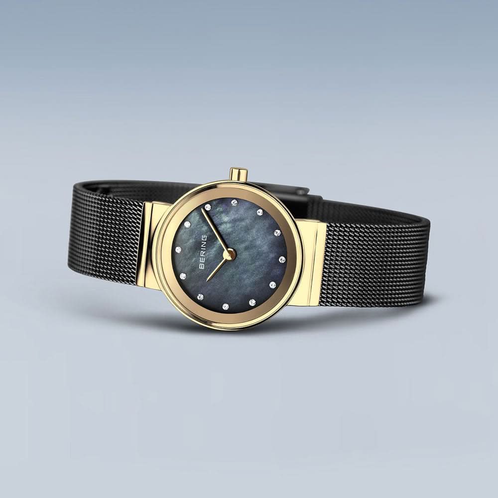 "Damklocka med blå urtavla, guldfärgad infattning och svart milanesisk armband."