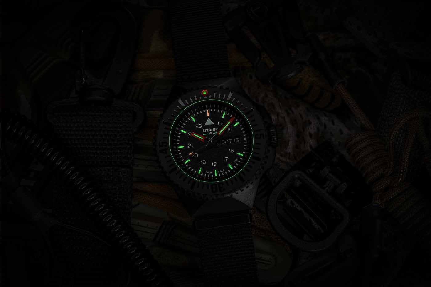 Herrklocka i mörk miljö med grönt lysande markeringar, svart textilarmband