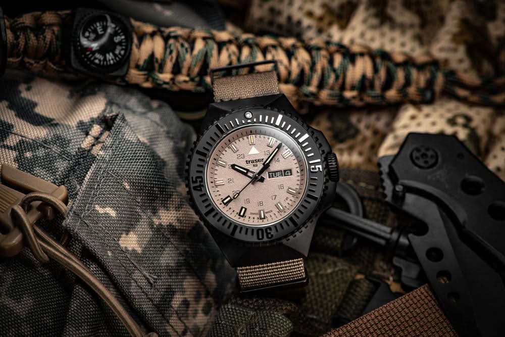 Herrarmbandsur med svart infattning, beige urtavla och beige textilarmband.