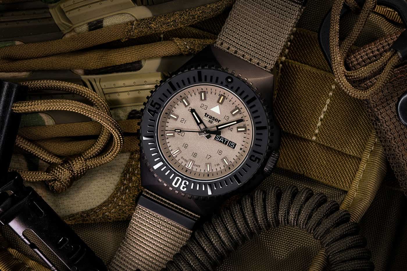 Herrklocka med beige textilarmband, svart infattning och beige urtavla.