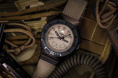 Herrklocka med beige textilarmband, svart infattning och beige urtavla.