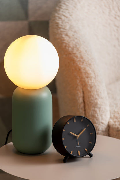Karlsson Grace klocka på bord bredvid grön lampa, ljuset lyser